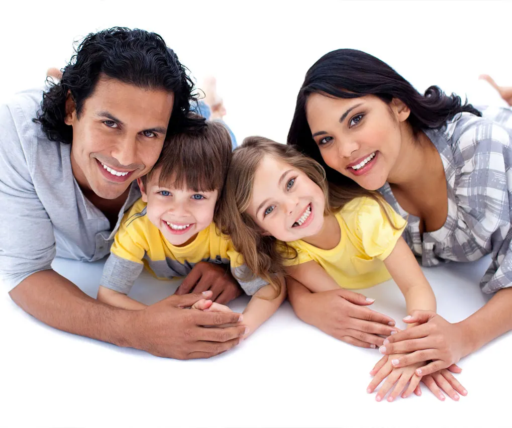 A family of four lying together and smiling up at the camera