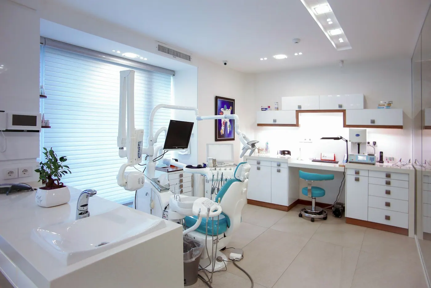 A bright, tidy dental treatment room with the chair, light and cabinetry