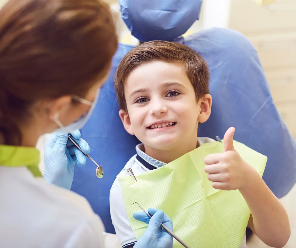A young patient giving a thumbs up in the dental chair