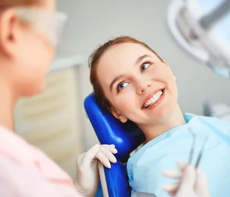 A relaxed patient smiling in the dental chair while a clinician prepares to examine